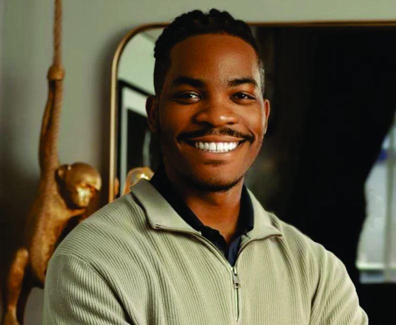 Kennedy Ekezie smiling in a grey quarter-zip sweater