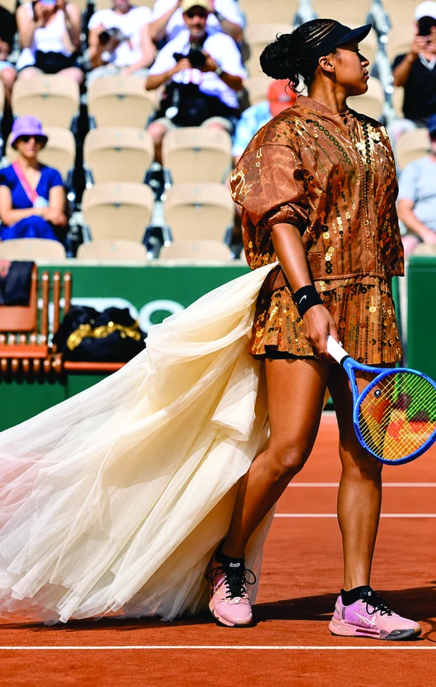 Naomi Osaka in bronze sequins with a long tulle train on clay